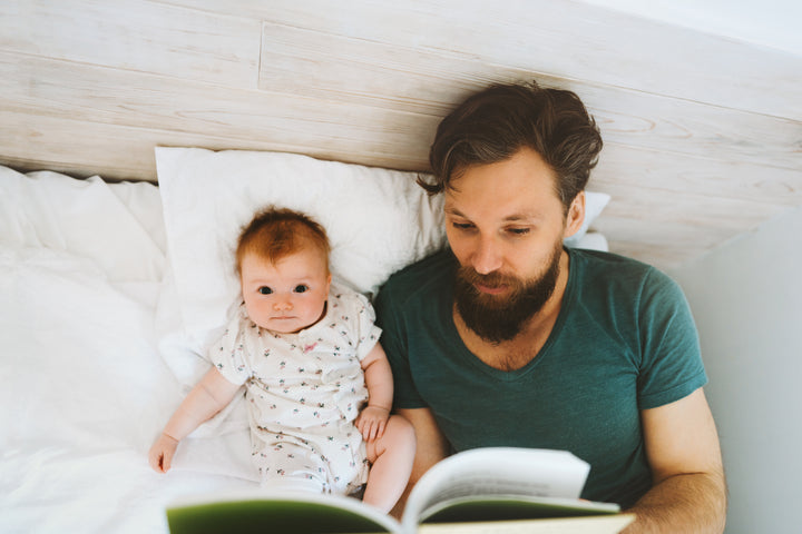 father reads storybook to infant daughter