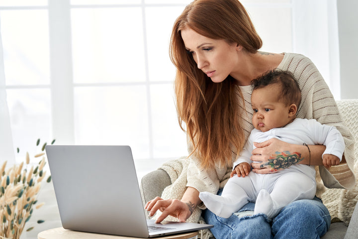 single mother working on computer with baby on her lap